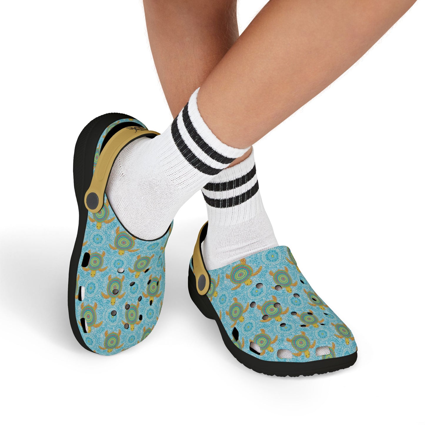 Blue patterned slip-on clogs with tan strap on feet with white socks and black stripes
