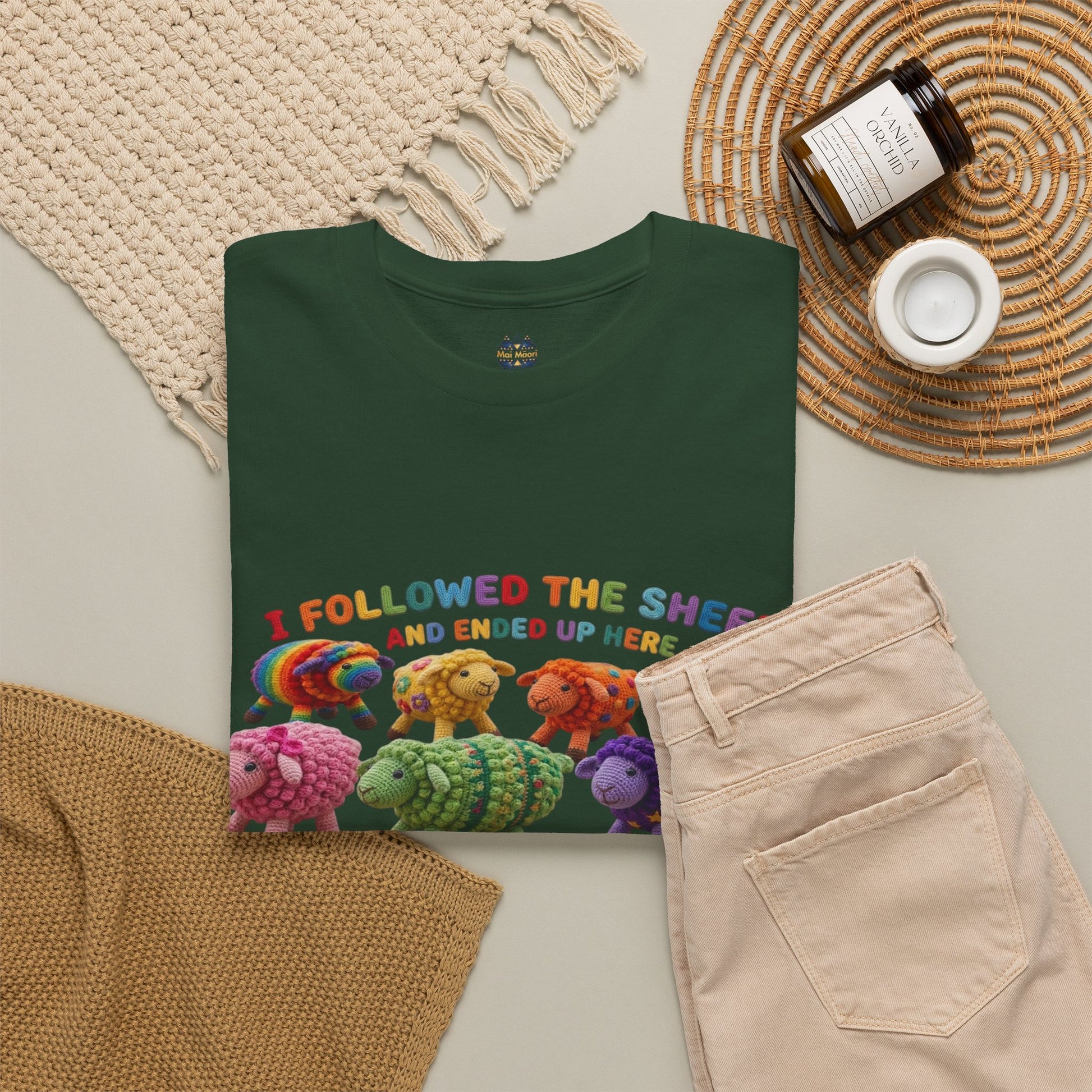 Forest green T-shirt laid flat with colorful sheep graphic across the chest