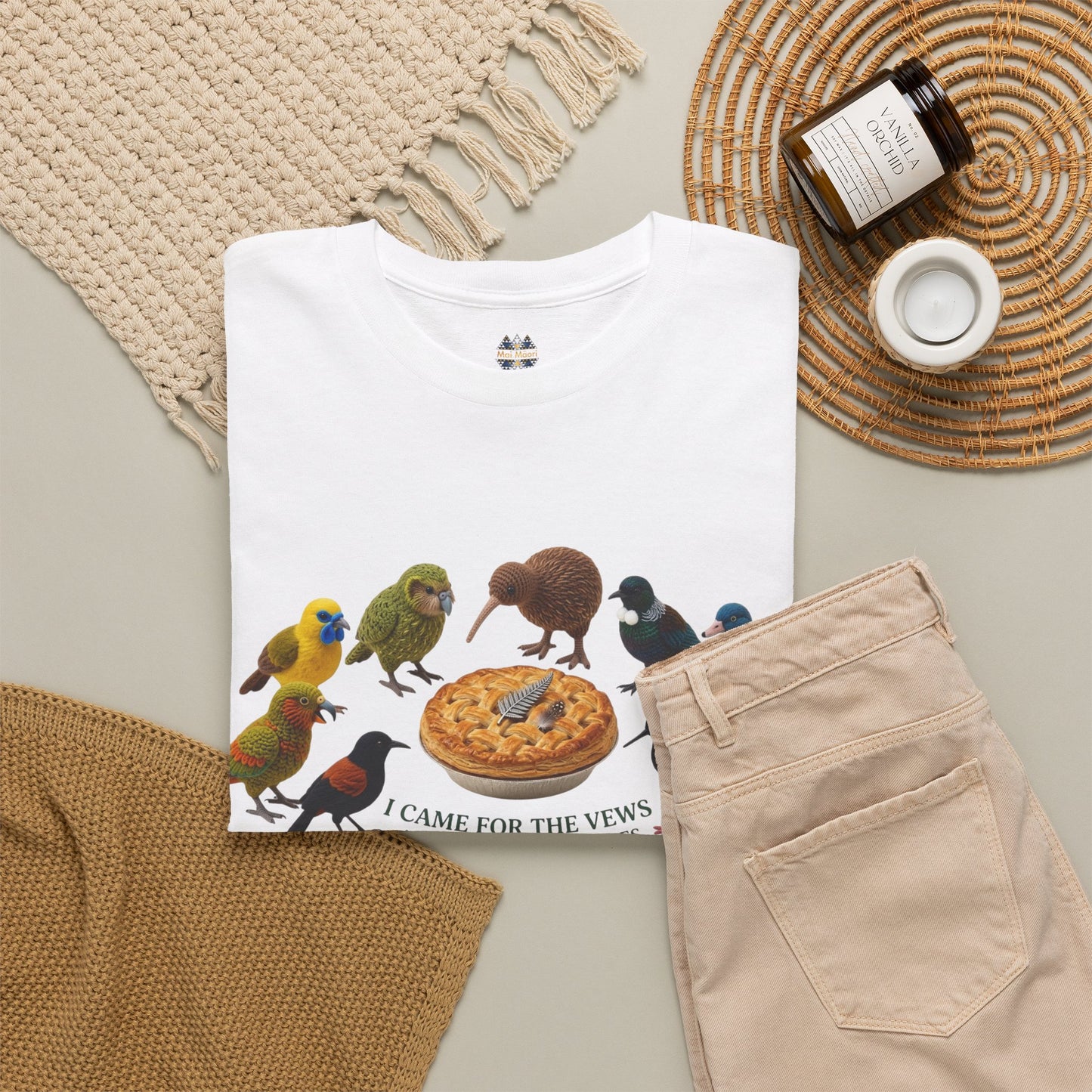 White T-shirt with birds-and-pie front graphic, styled with beige pants nearby.