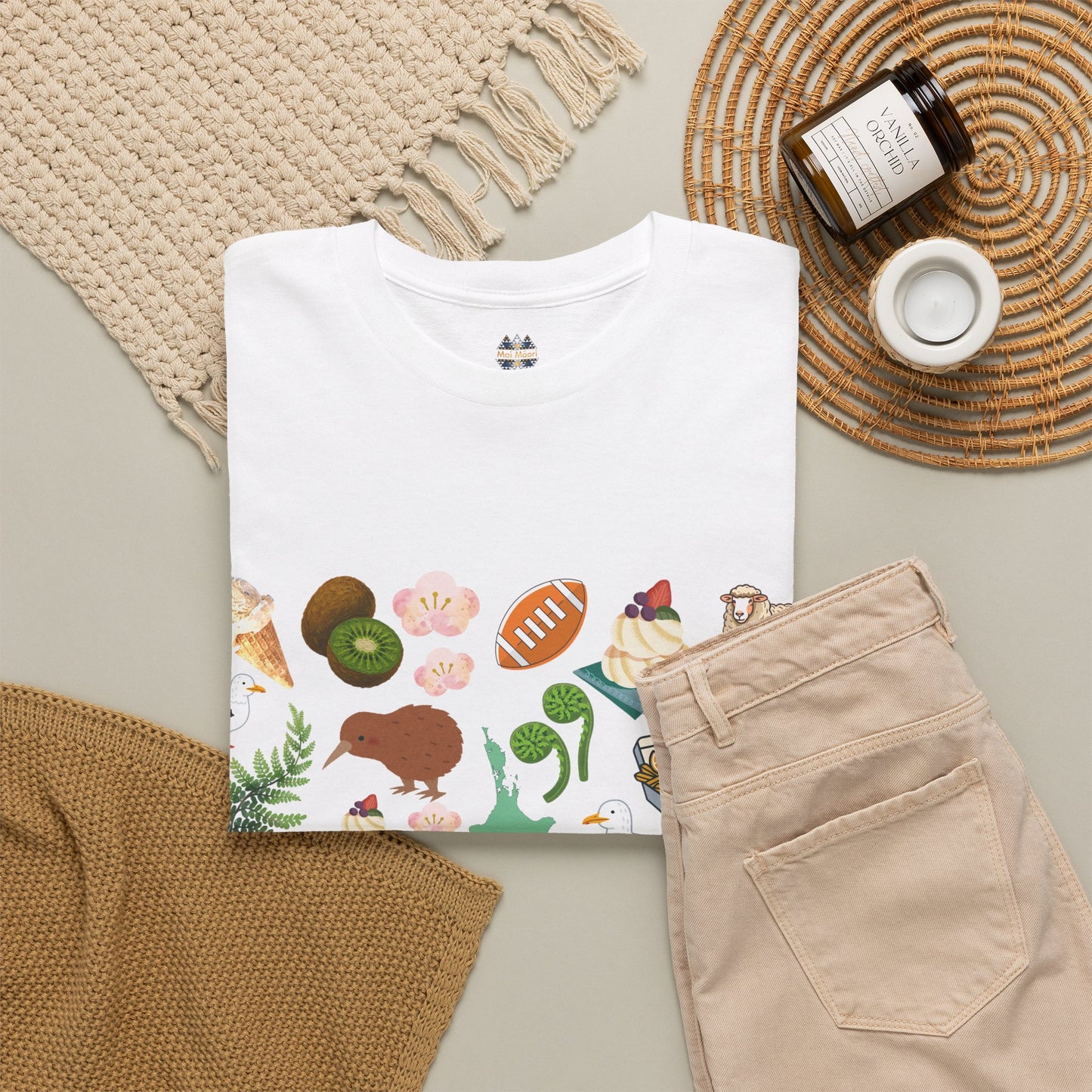 White crewneck T-shirt folded with small Kiwiana icon and colorful wildlife border