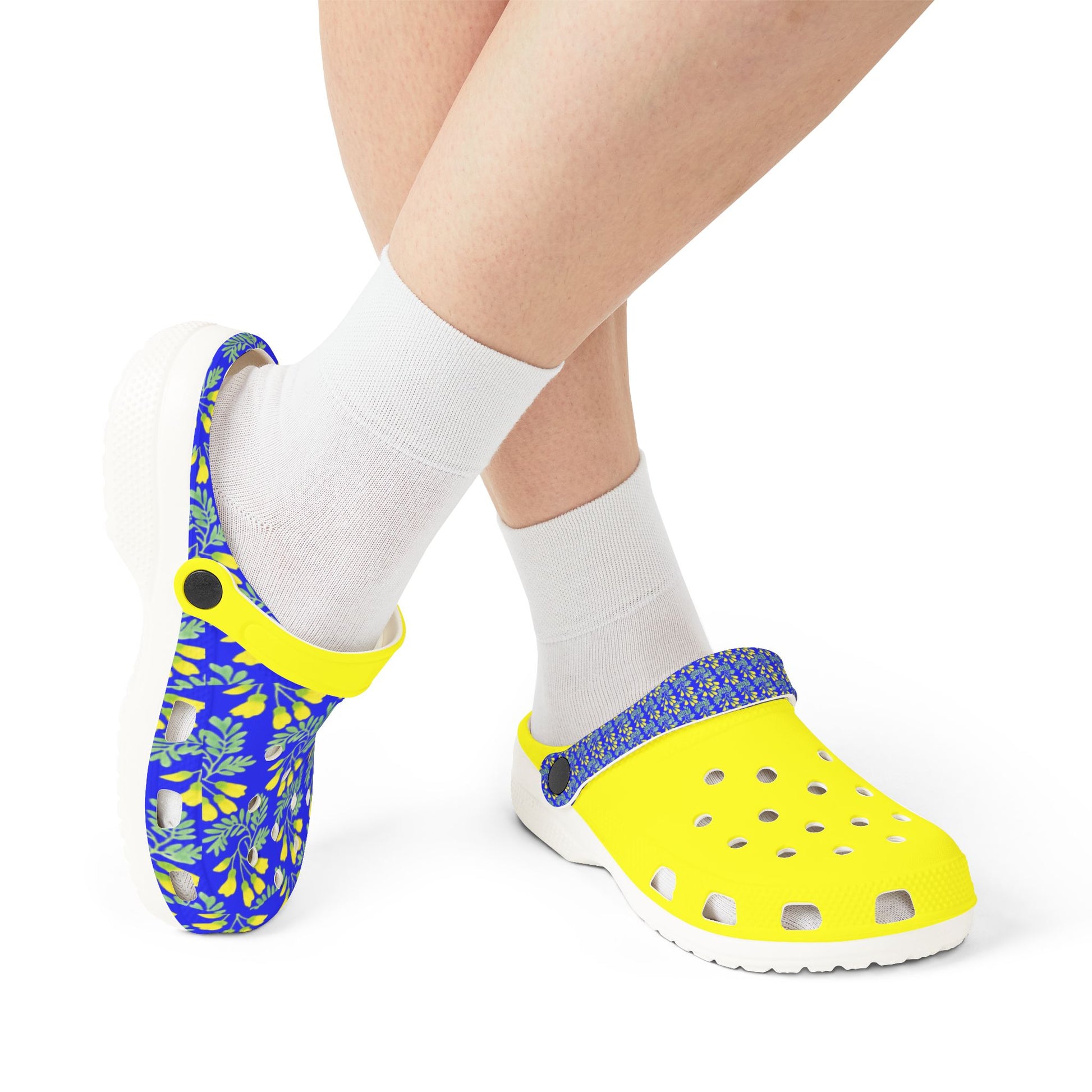 Kōwhai slip-on clogs with yellow base, blue leaf print, worn with white socks