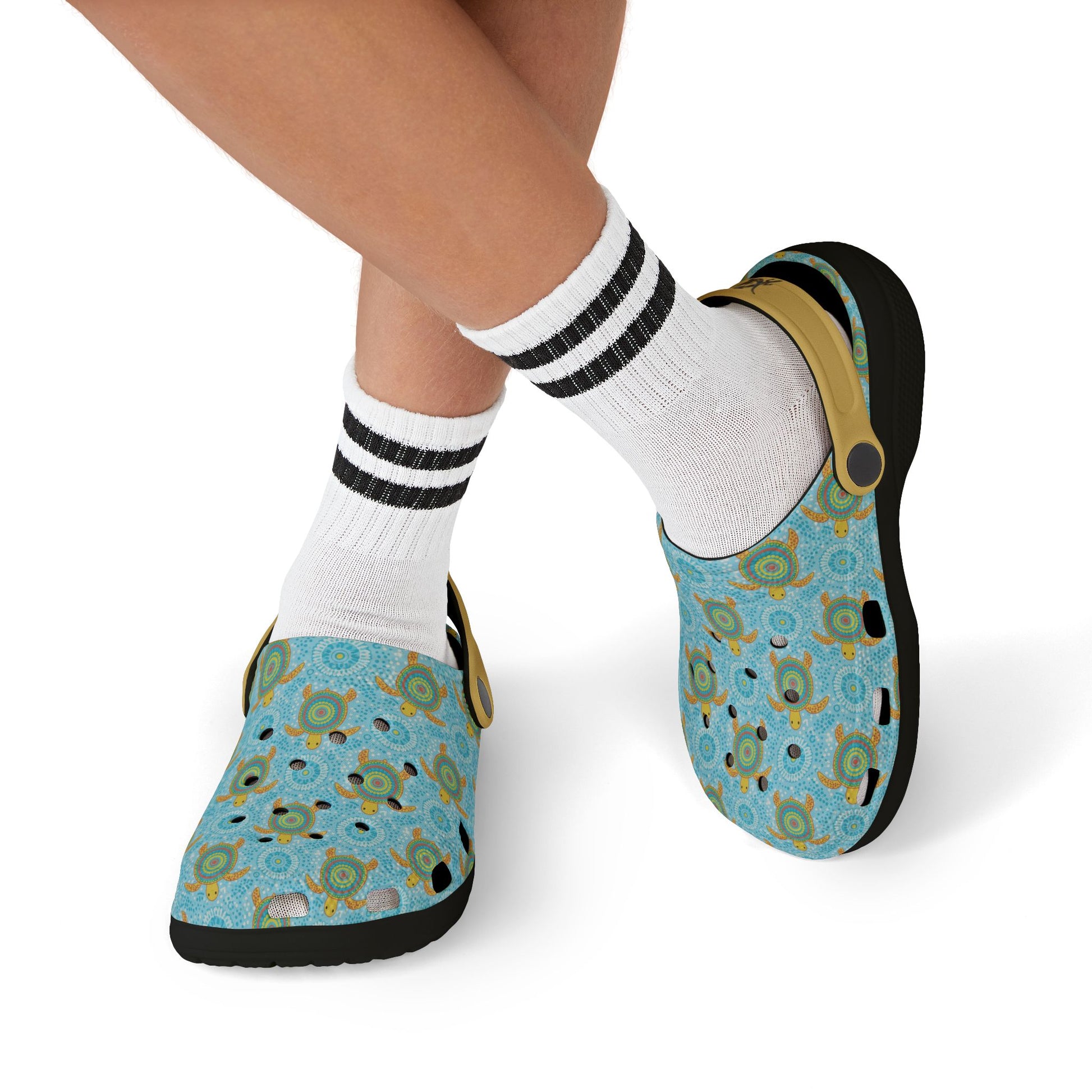 Person wearing blue patterned clogs with tan heel strap and white socks with black stripes