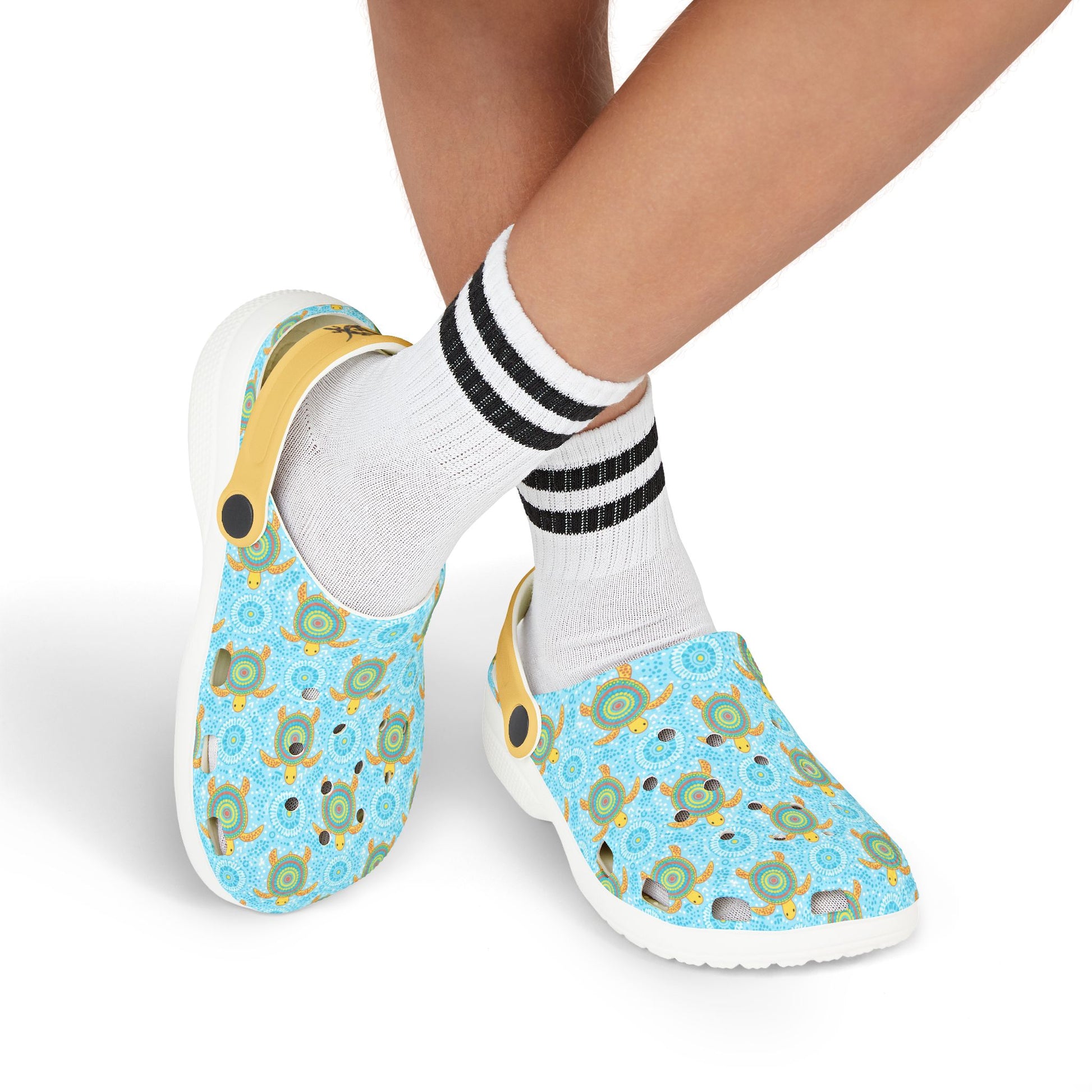 Light blue turtle-pattern clog shoes worn with white socks; side view of yellow strap
