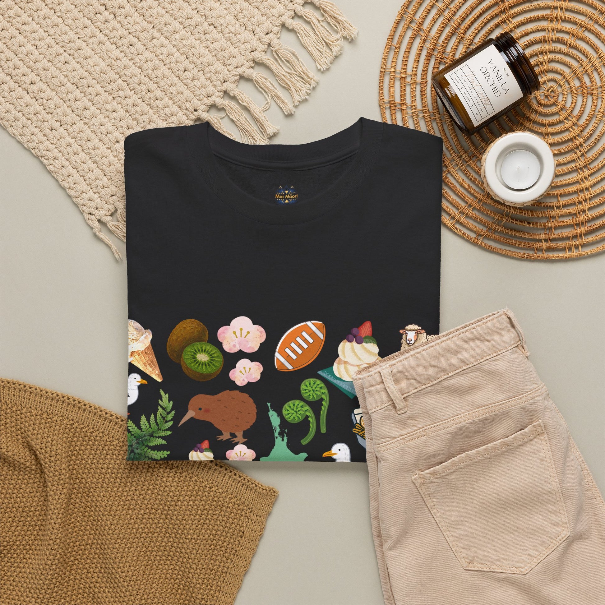 Black T-shirt with colorful Kiwiana-style illustration across the chest; crew neck