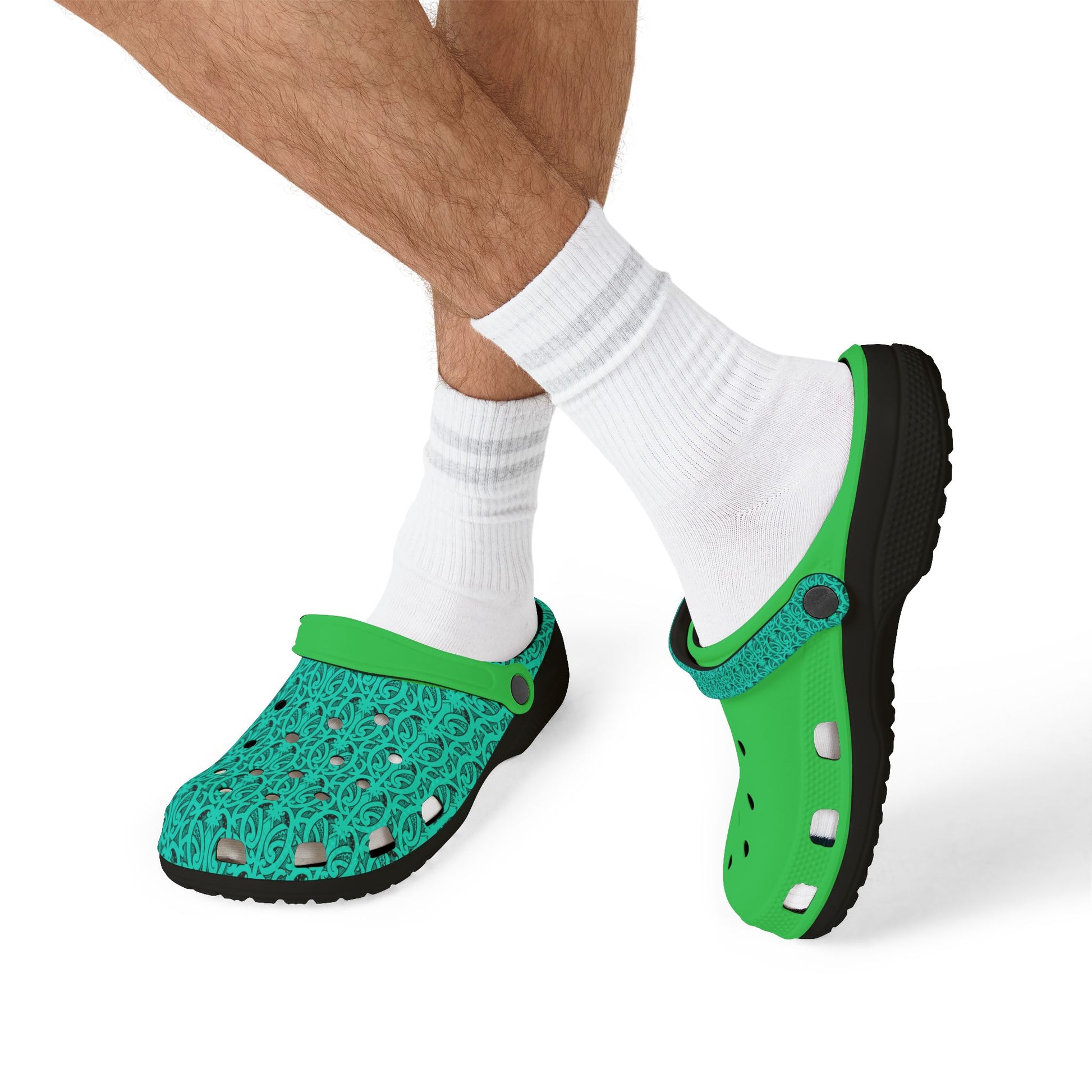 Green and teal clogs worn with white socks; perforated toe and black outsole visible