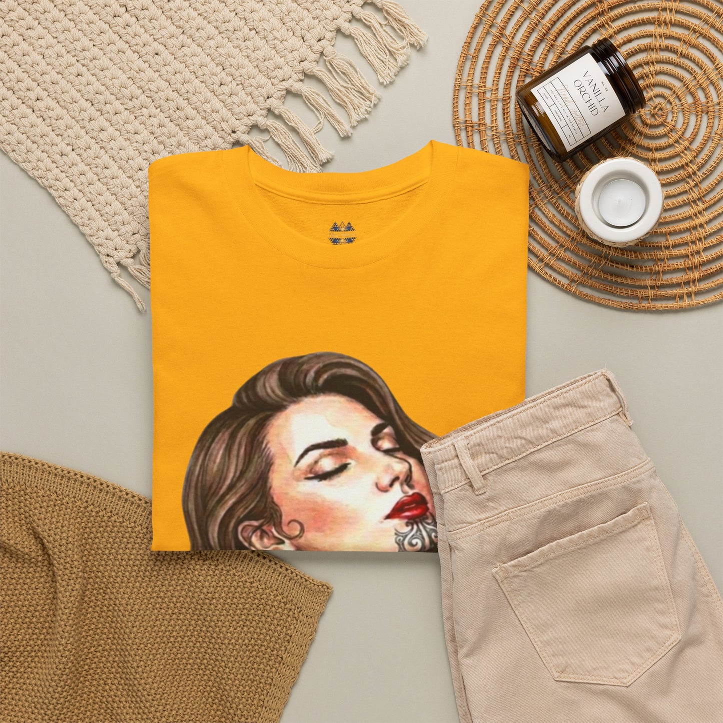 Mustard yellow t-shirt with close-up portrait graphic and small chest logo.