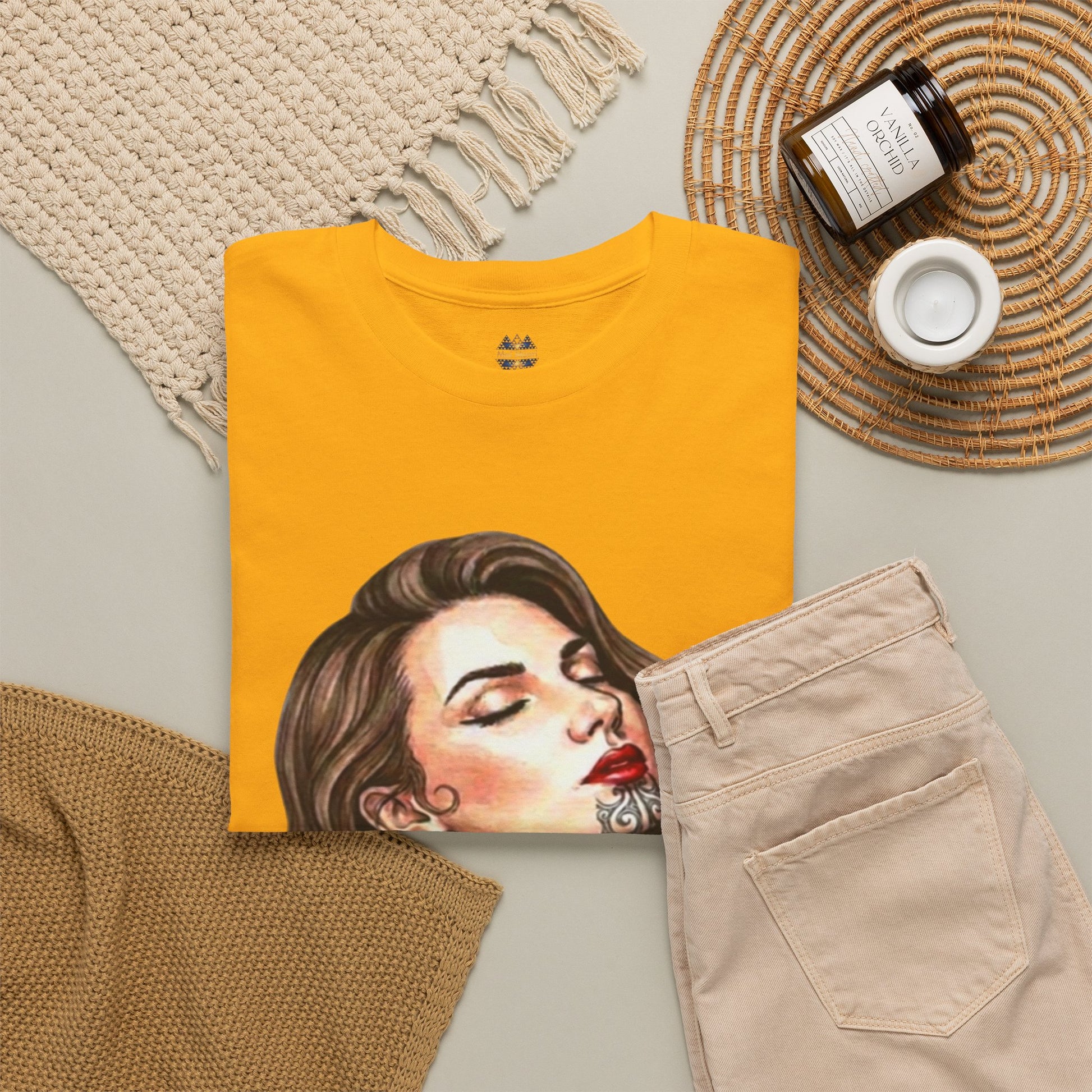 Mustard yellow t-shirt with close-up portrait graphic and small chest logo.