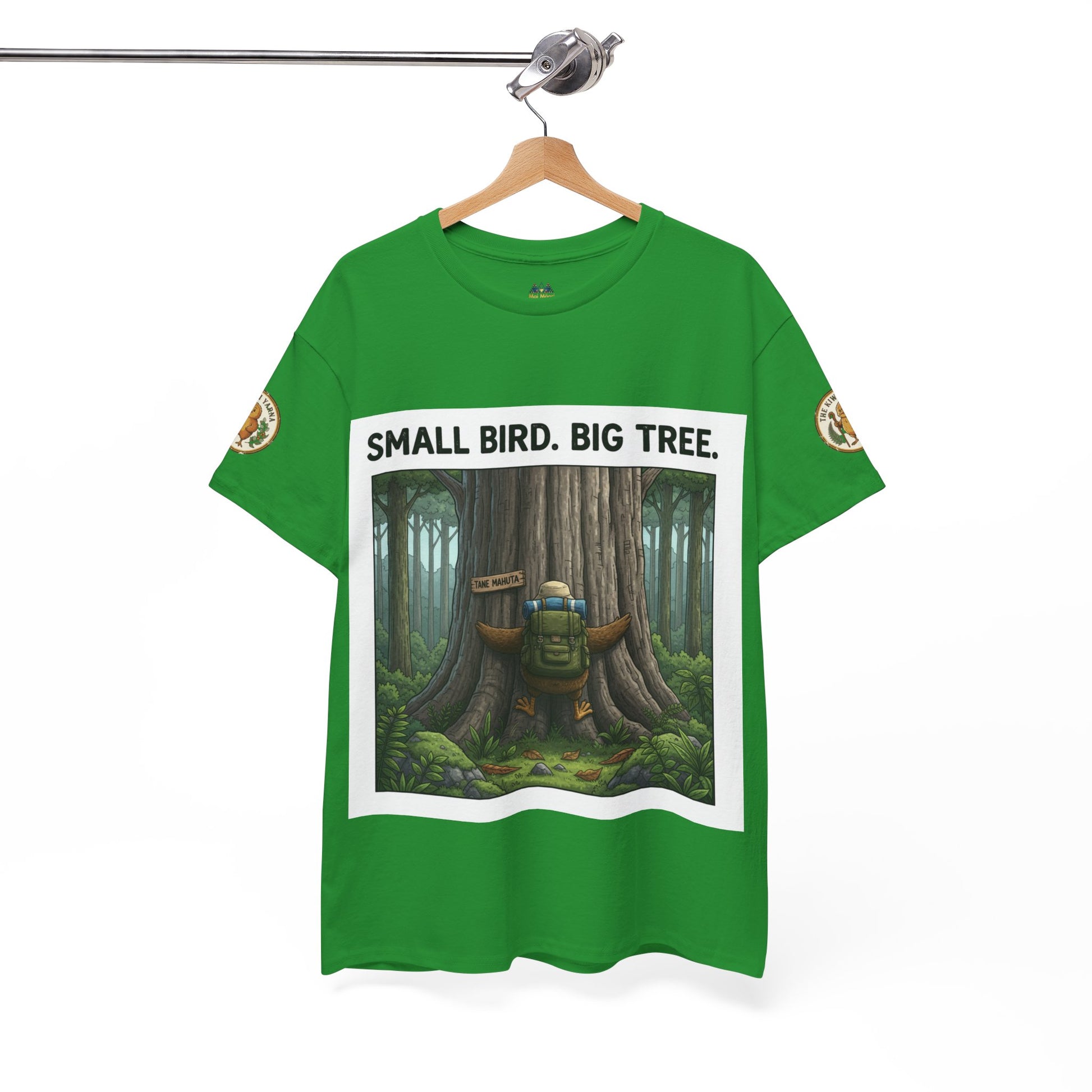 Green T-shirt on hanger with centered forest artwork and 'SMALL BIRD. BIG TREE' text
