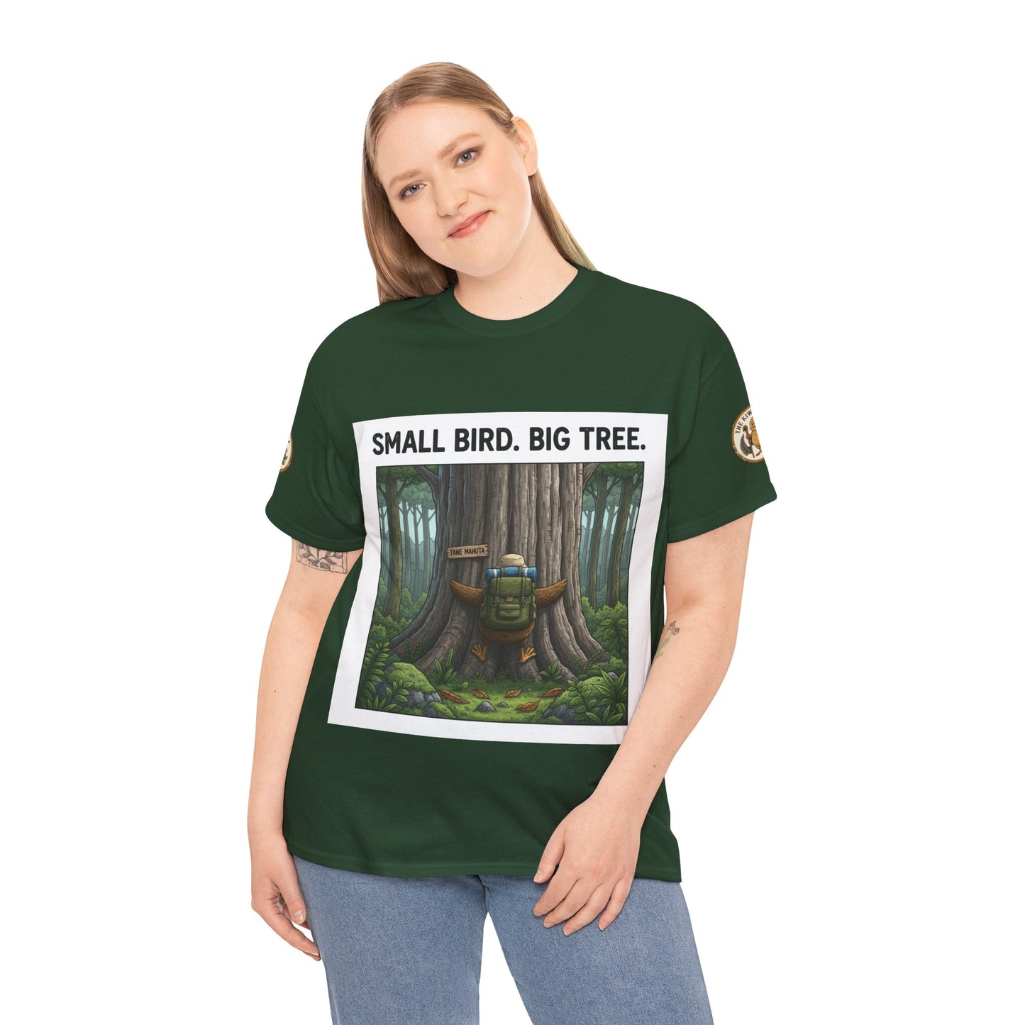 Model wearing dark green graphic T-shirt with forest tree artwork and “SMALL BIRD. BIG TREE.”