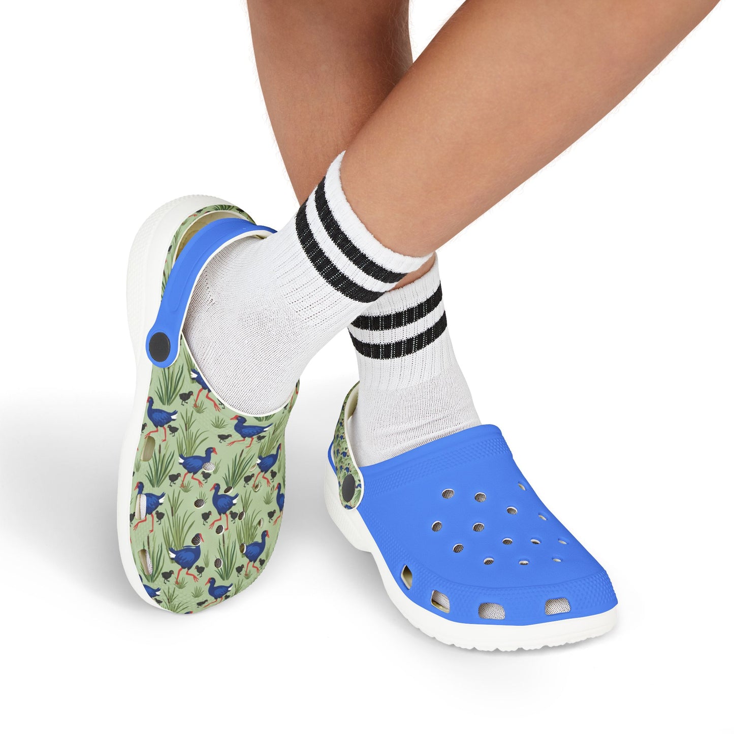 Kids clogs worn side-by-side with white socks; green print and blue top, white sole.