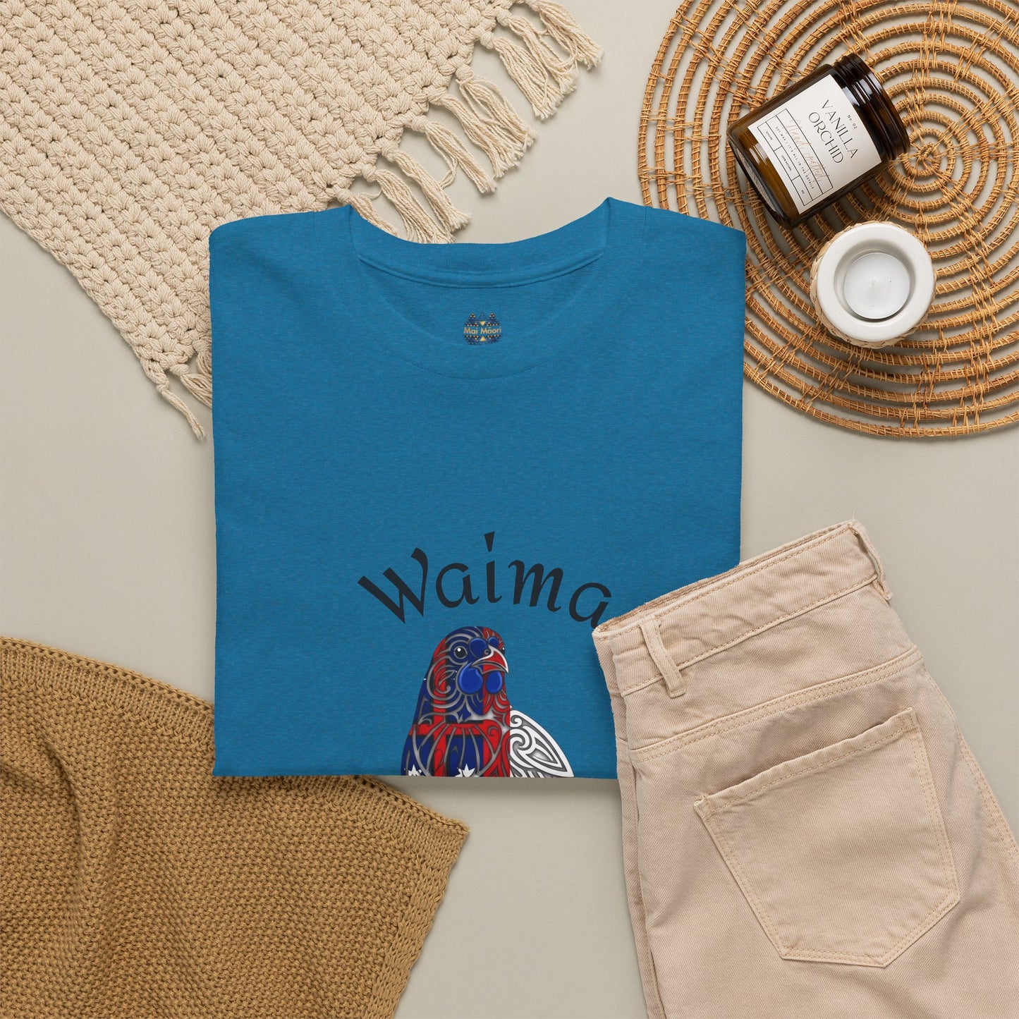 Blue T-shirt flat lay with Waima Hokiana bird front text and small chest logo at collar