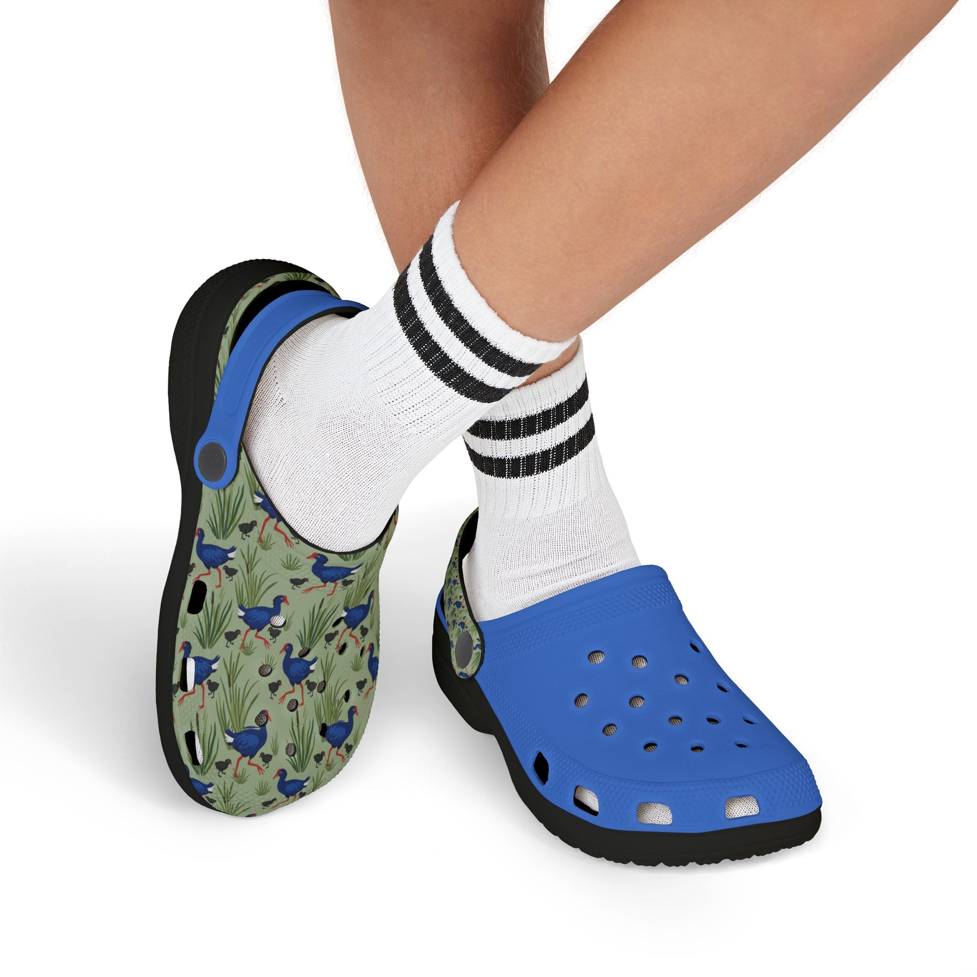 Kids clogs on feet, patterned left shoe and blue right shoe, white socks with stripes.