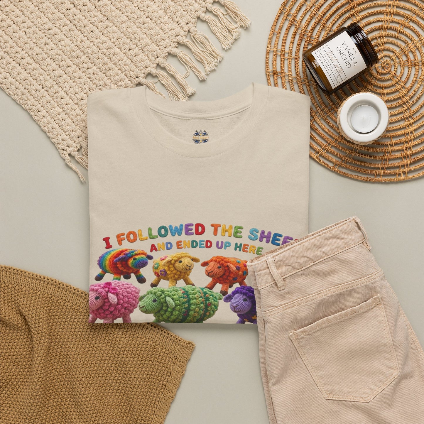 Beige short-sleeve T-shirt with colorful sheep graphic, shown with styled accessories nearby