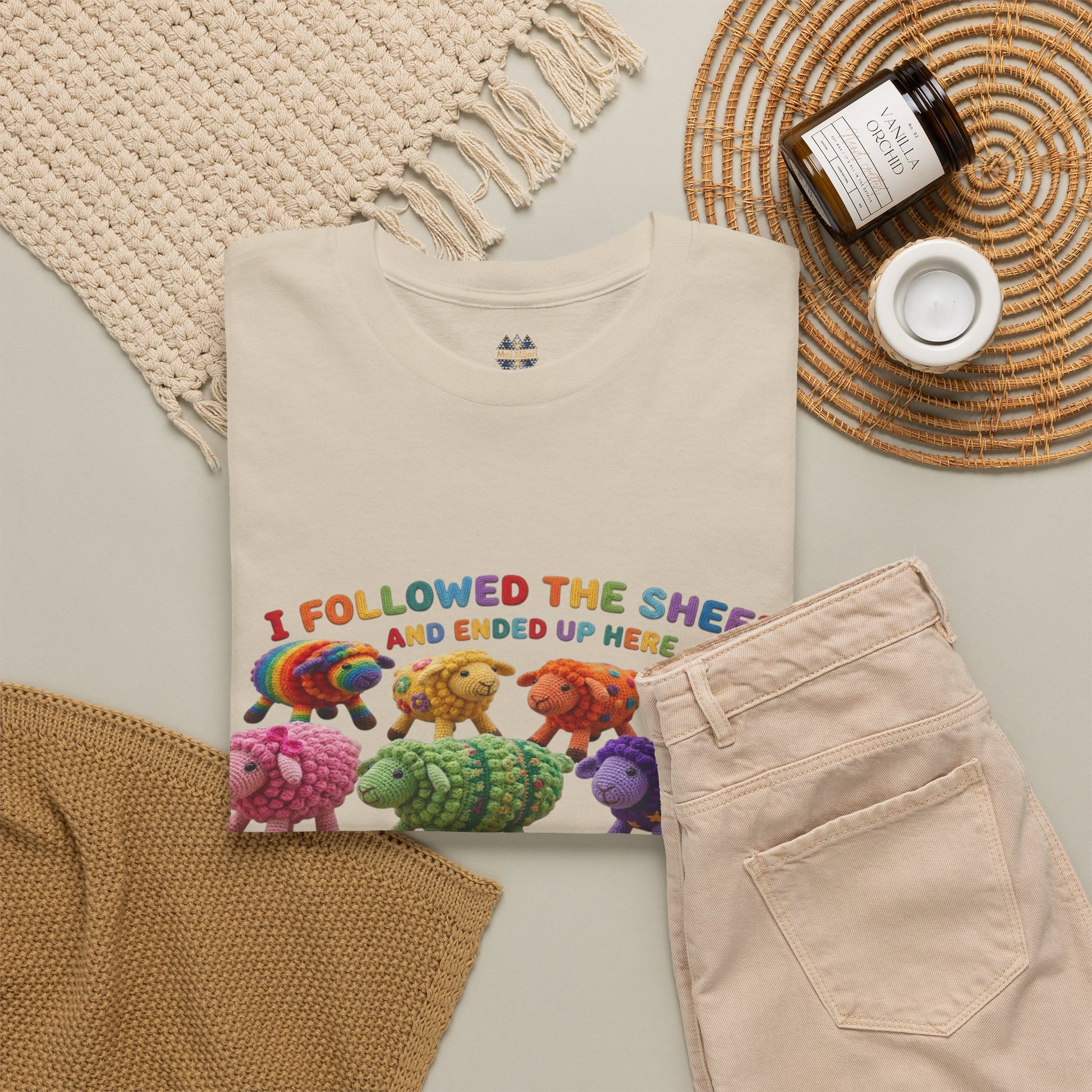 Beige short-sleeve T-shirt with colorful sheep graphic, shown with styled accessories nearby