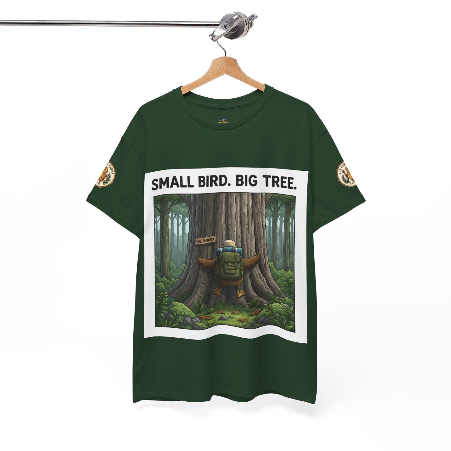 Dark green graphic T-shirt on hanger with forest tree artwork and “SMALL BIRD. BIG TREE.”