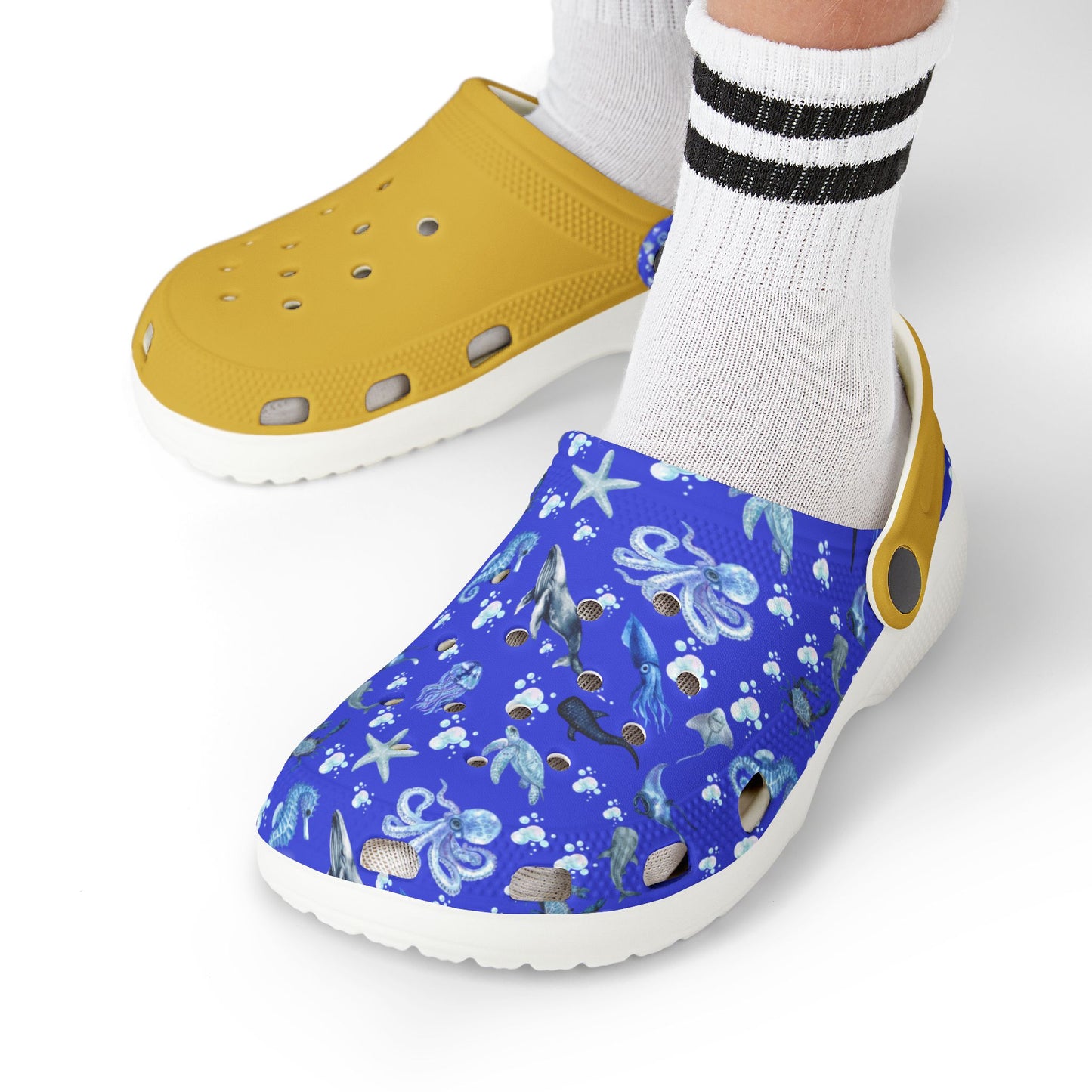 Kids' clog shoes on feet: yellow perforated shoe with blue sea-print outer, white sole.