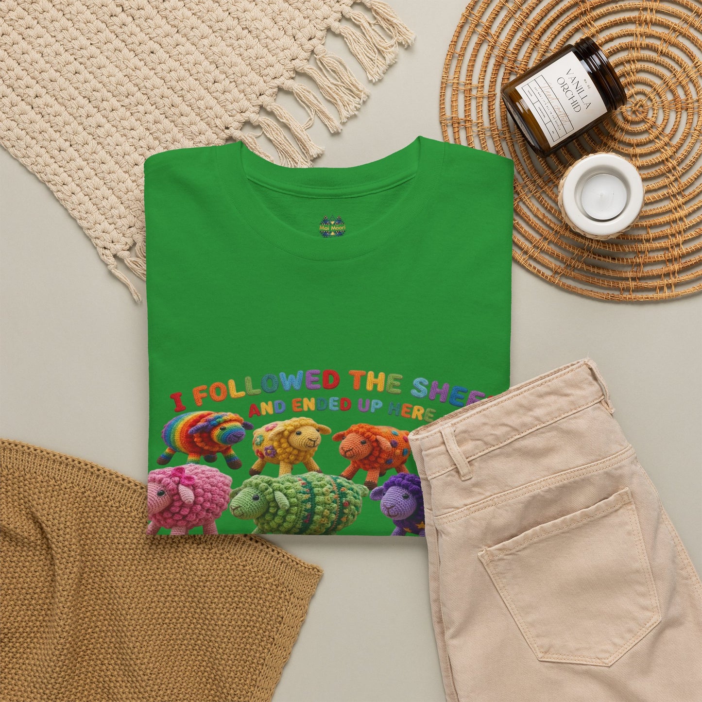 Green crew-neck t-shirt folded flat with colorful sheep graphic on the front