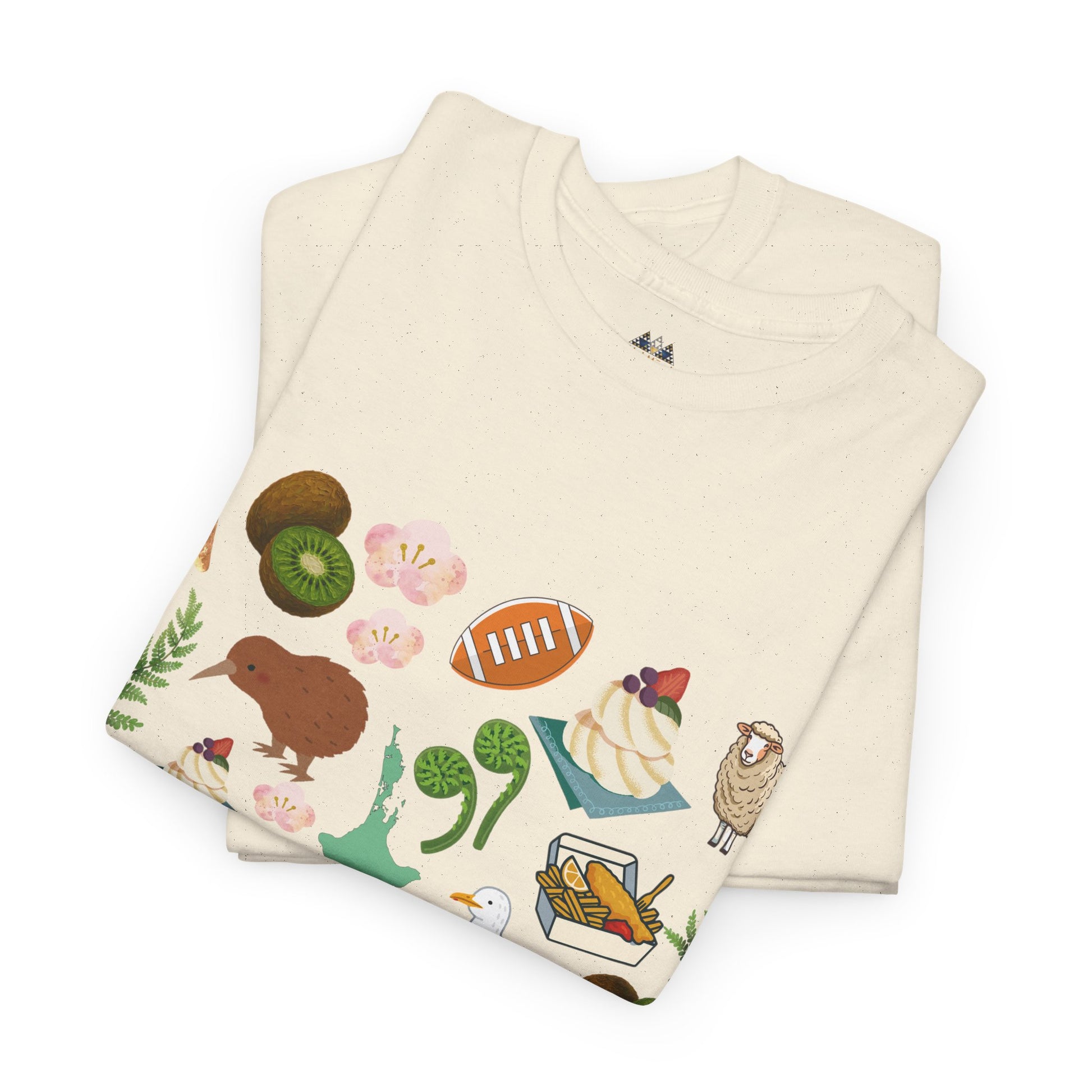 Cream graphic T-shirt stack with kiwi, flowers, fern, and shell illustrations at the hem