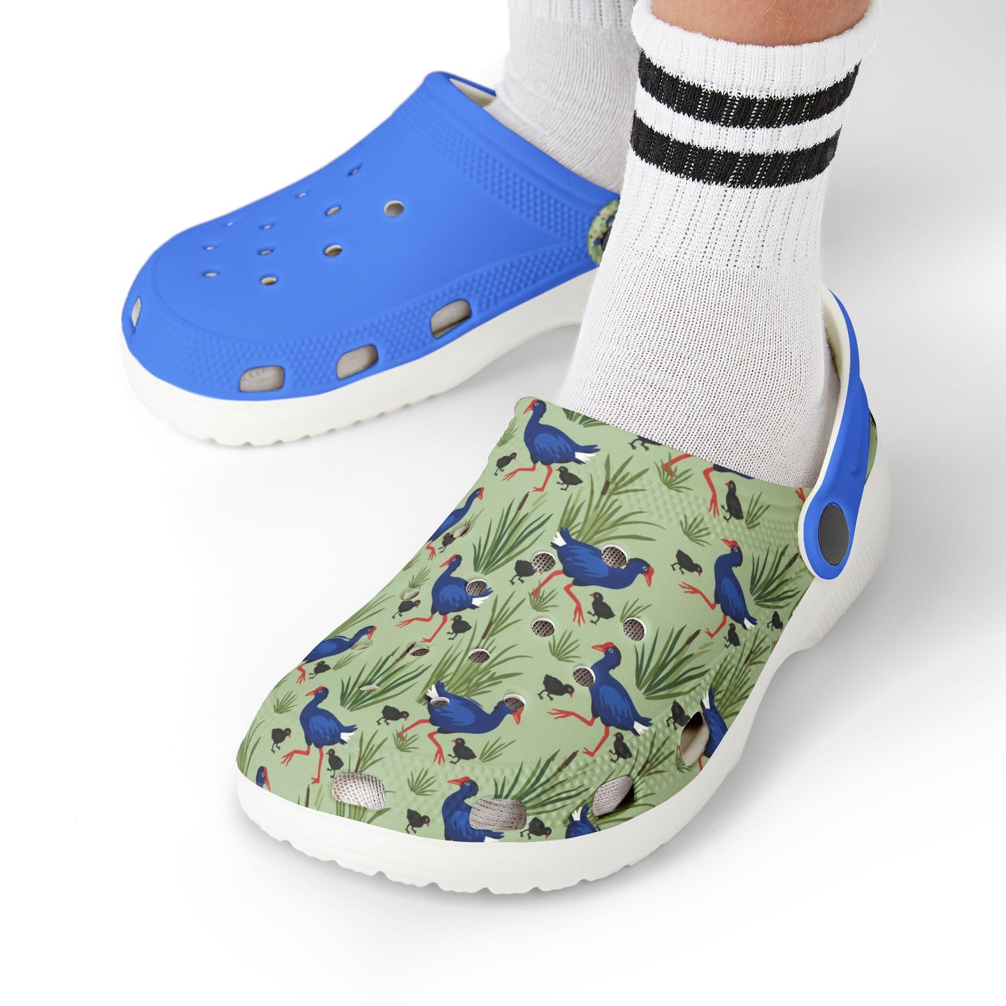Kids shoes worn with white socks; blue clogs with green animal print upper and white sole.
