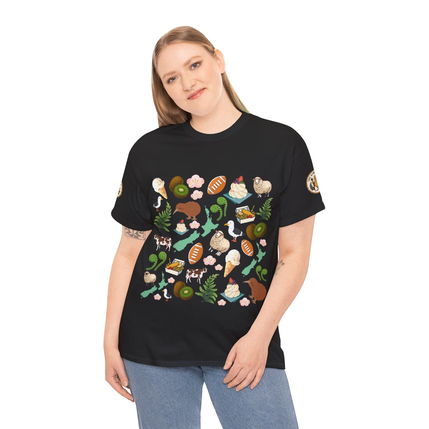 Kiwiana-themed T-shirt in black worn by model; front shows colorful wildlife and fern graphic