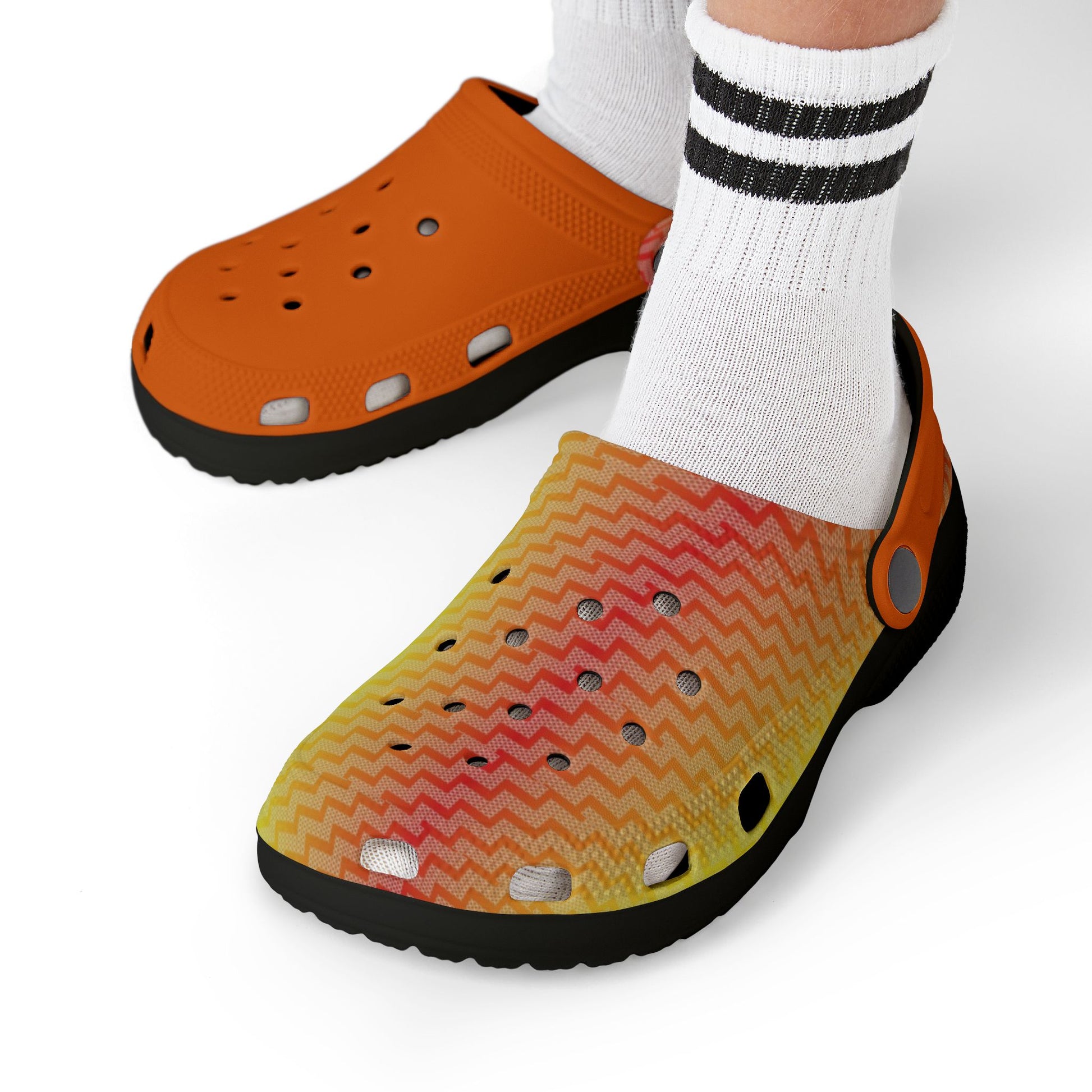 Orange clog worn with white socks; perforated upper and lime zigzag foot top.