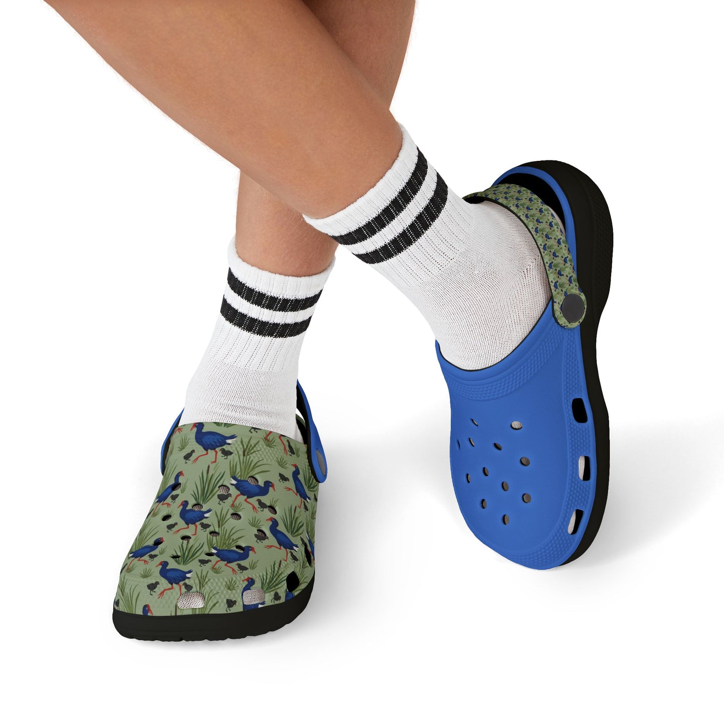 Kids clogs on feet, blue back and patterned front, white socks with black stripes.