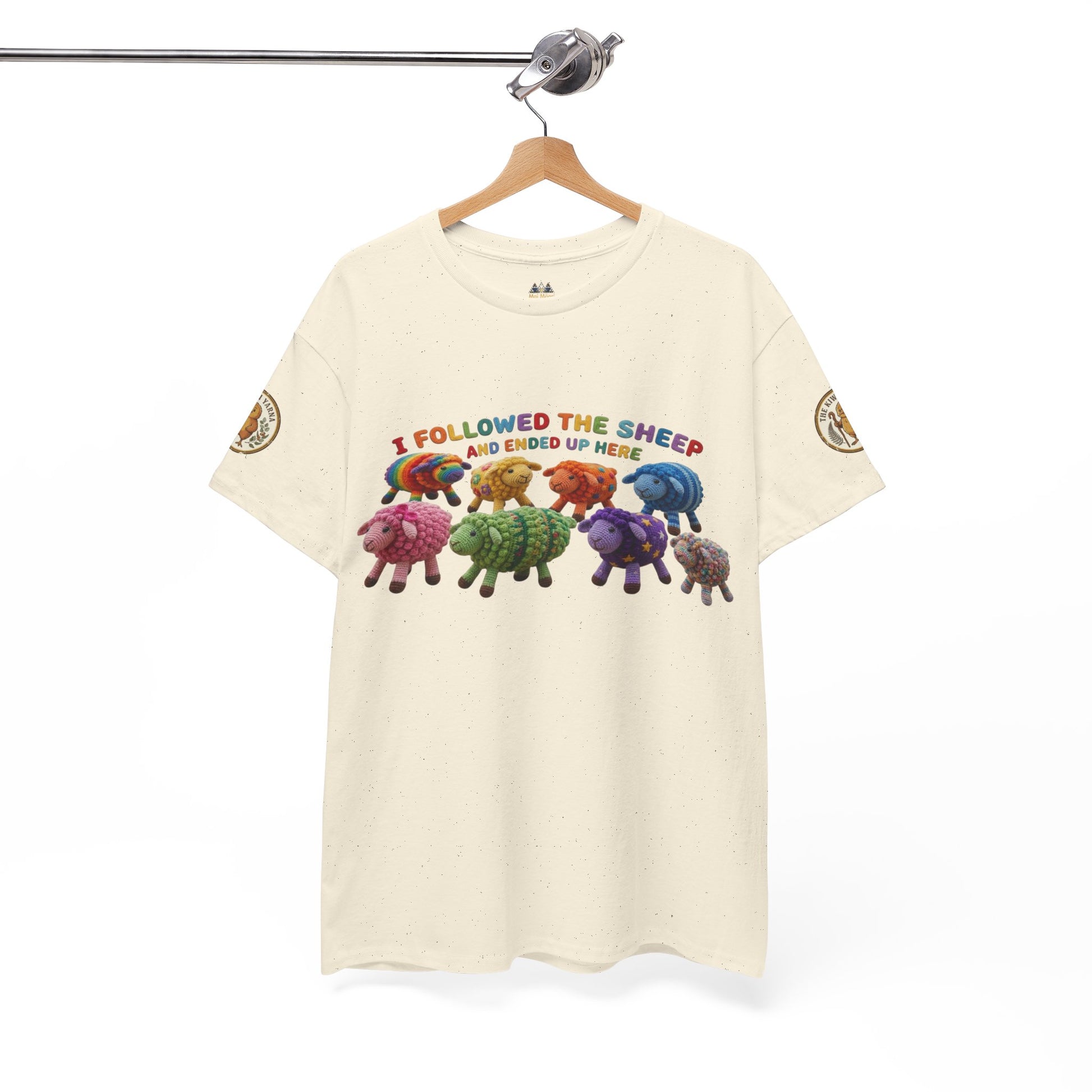 Cream graphic crewneck T-shirt hanging, showing colorful sheep herd with printed text.