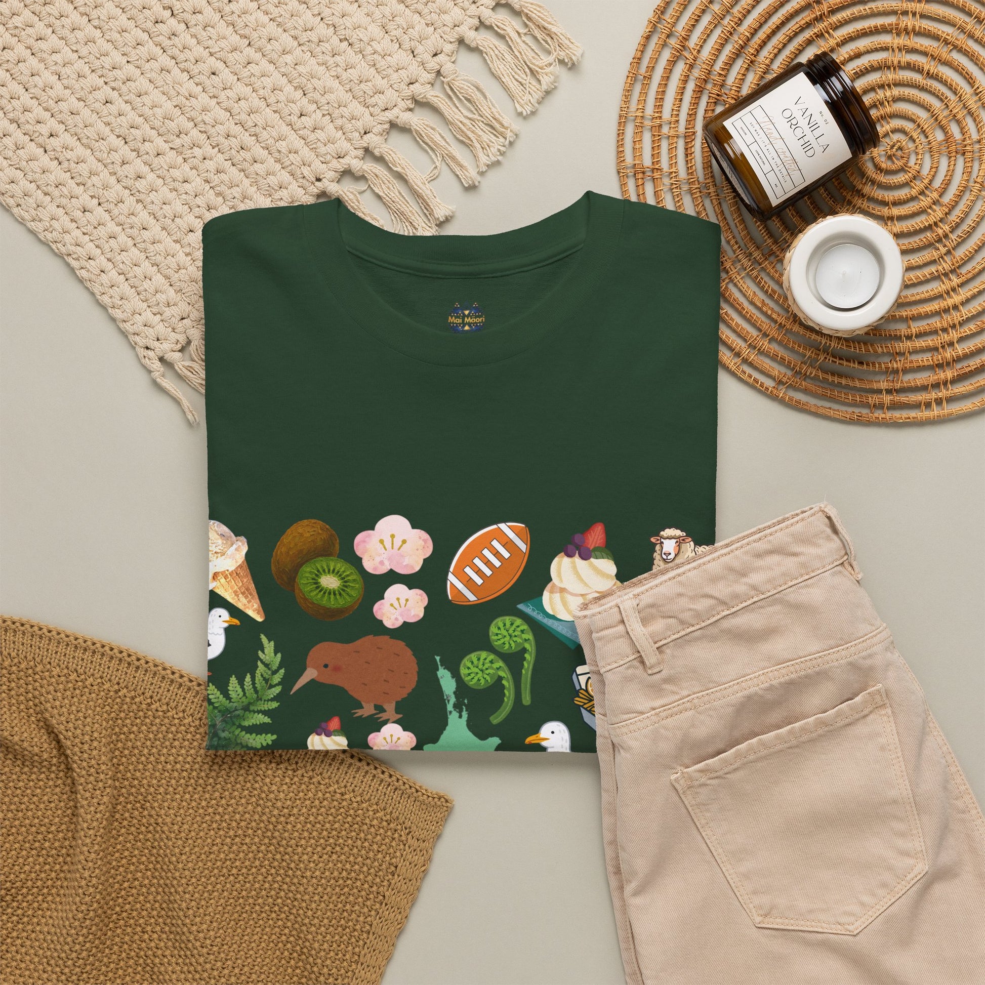 Green crew-neck short-sleeve T-shirt with colorful Kiwiana-style panel graphic across the front