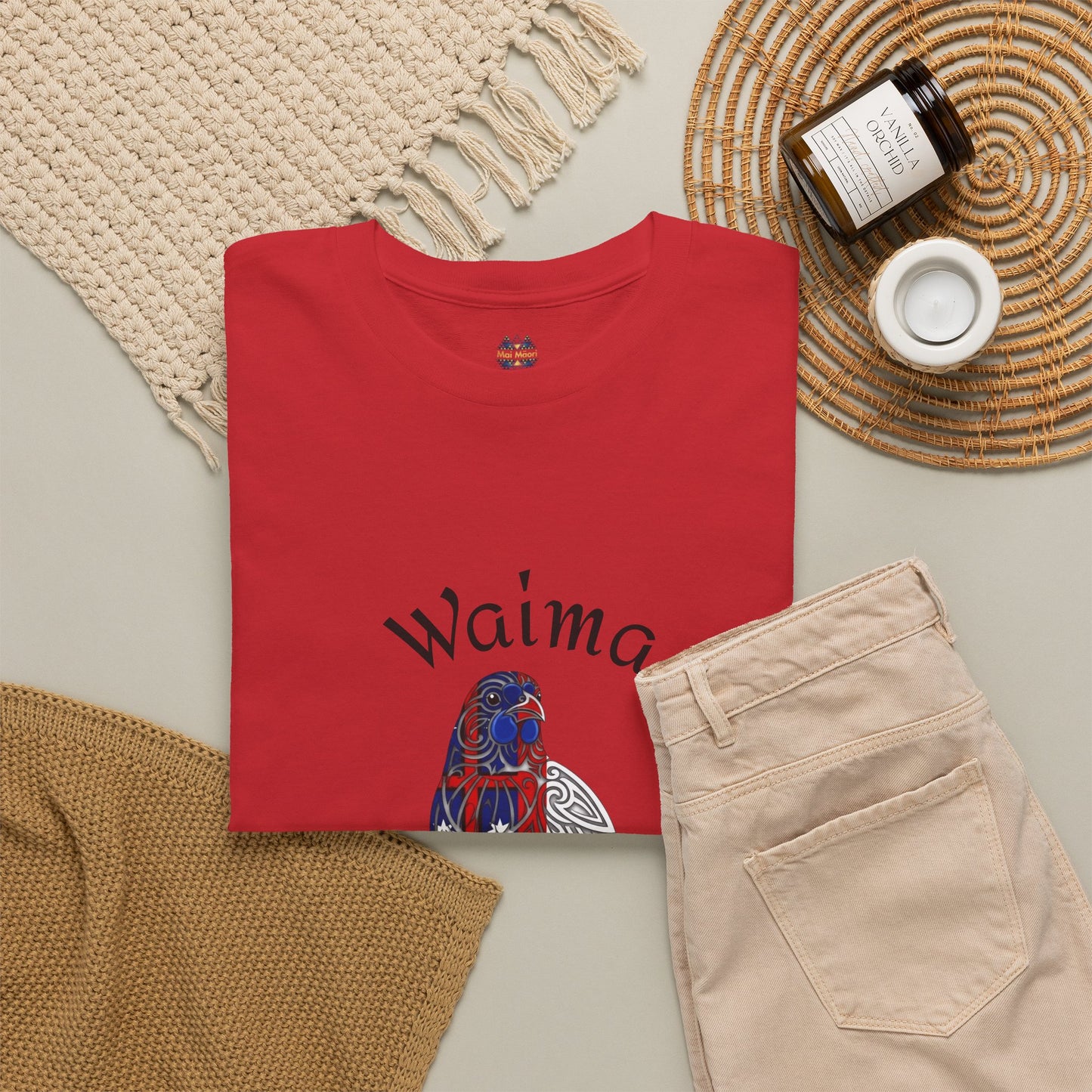 Red crewneck T-shirt on flat lay with bird graphic, shown with jeans and knit throw