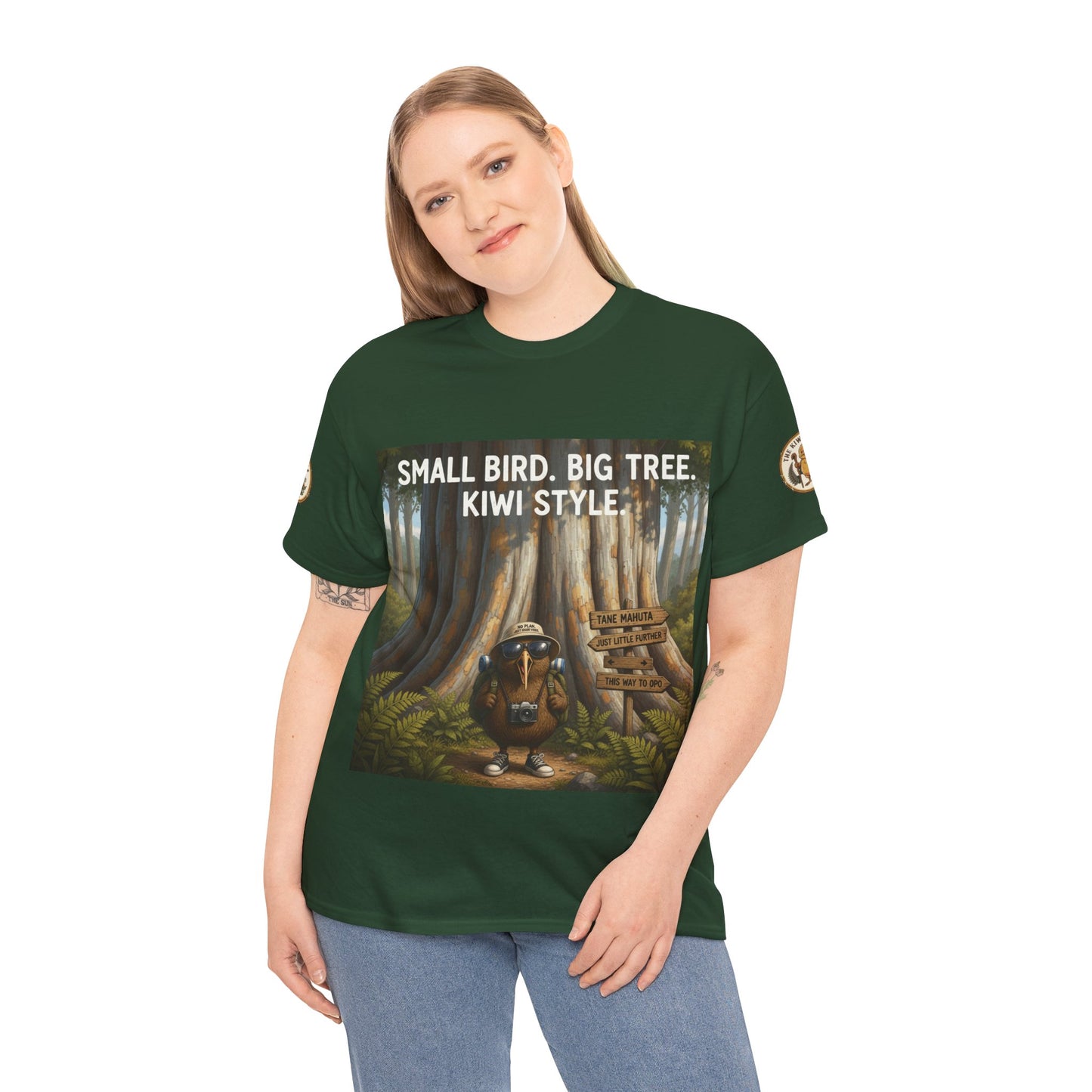 Dark green graphic t-shirt worn by model with front print: Small Bird Big Tree Kiwi Style